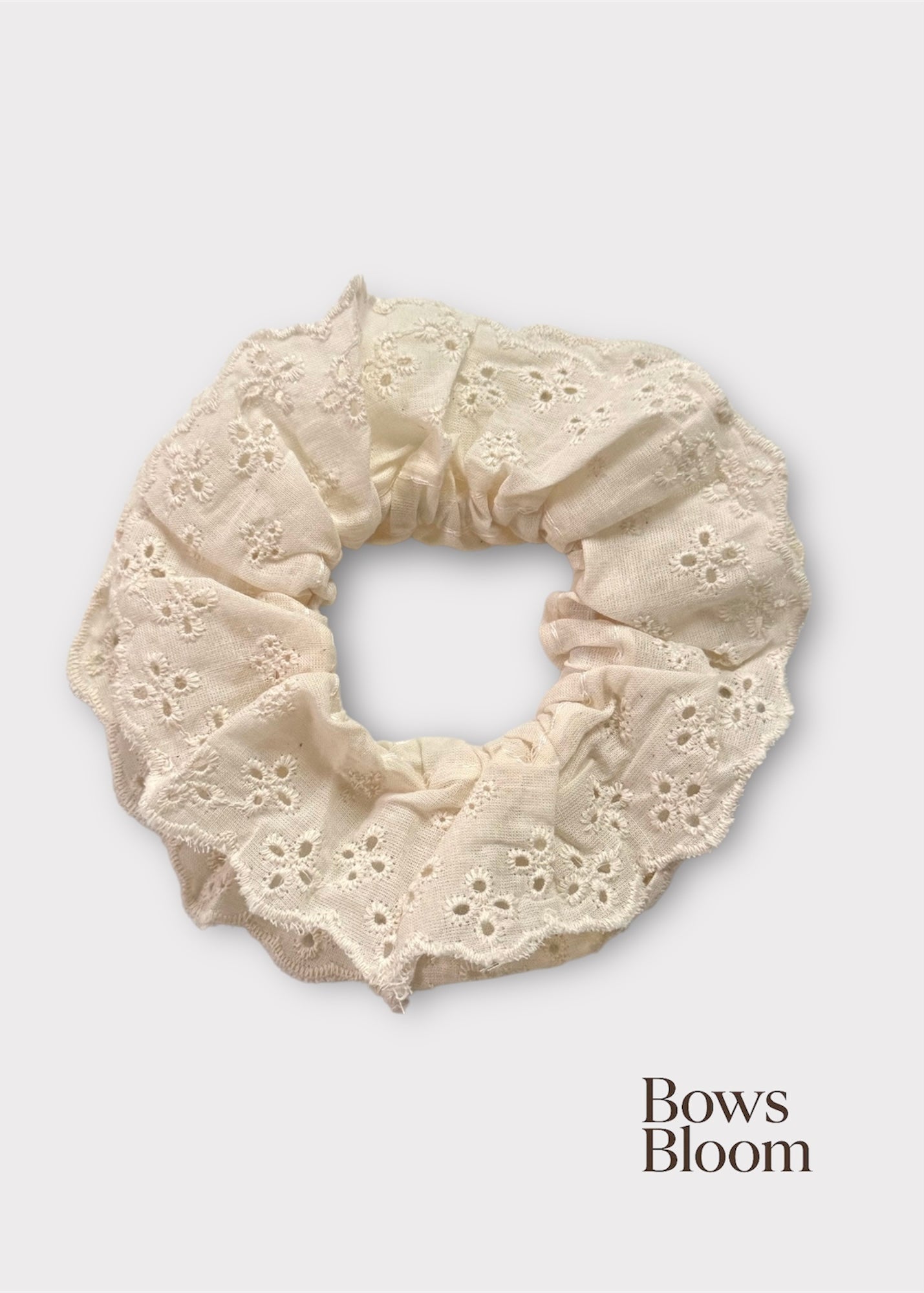 Ivory eyelet lace scrunchie with scalloped ruffle, full product on light background.