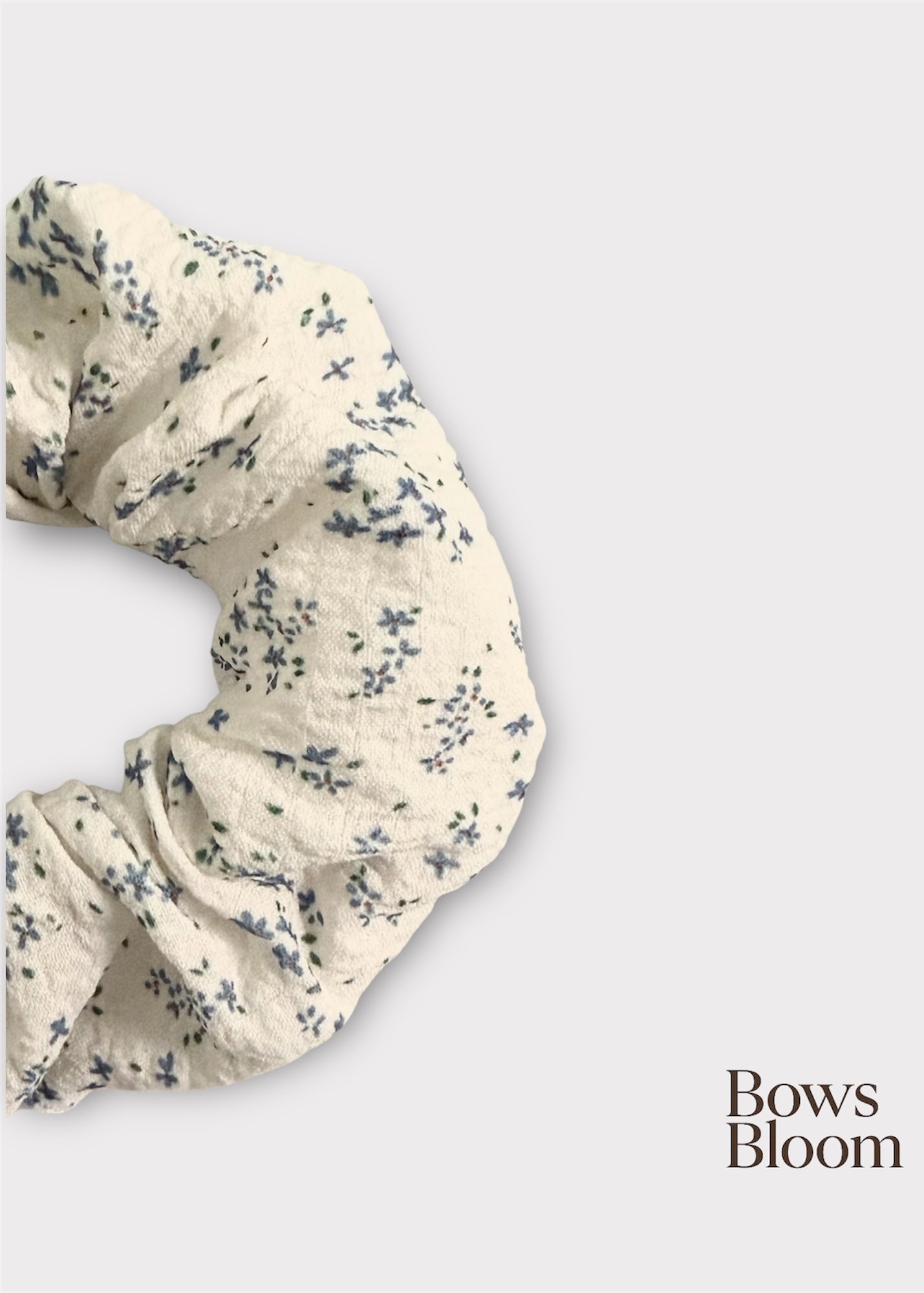 Close-up of white textured scrunchie with blue ditsy flowers showing crinkled fabric