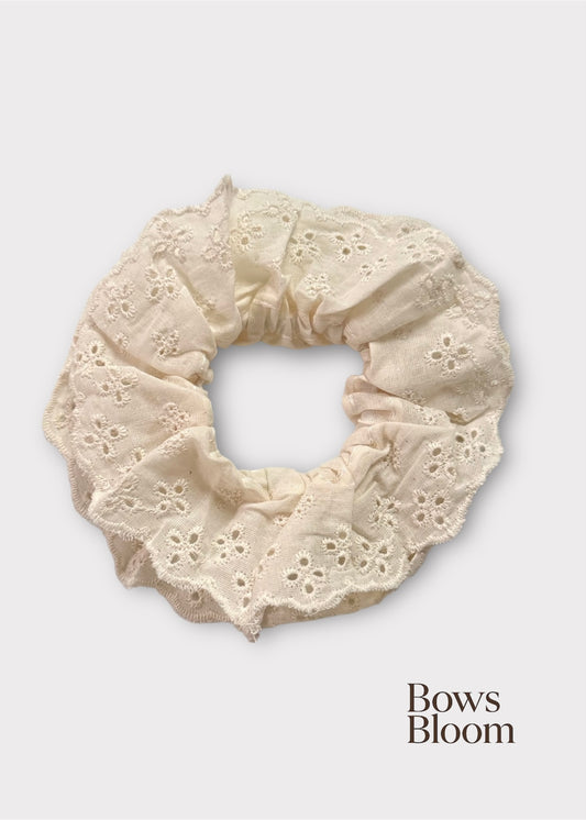 Ivory eyelet lace scrunchie with scalloped ruffle, full product on light background.