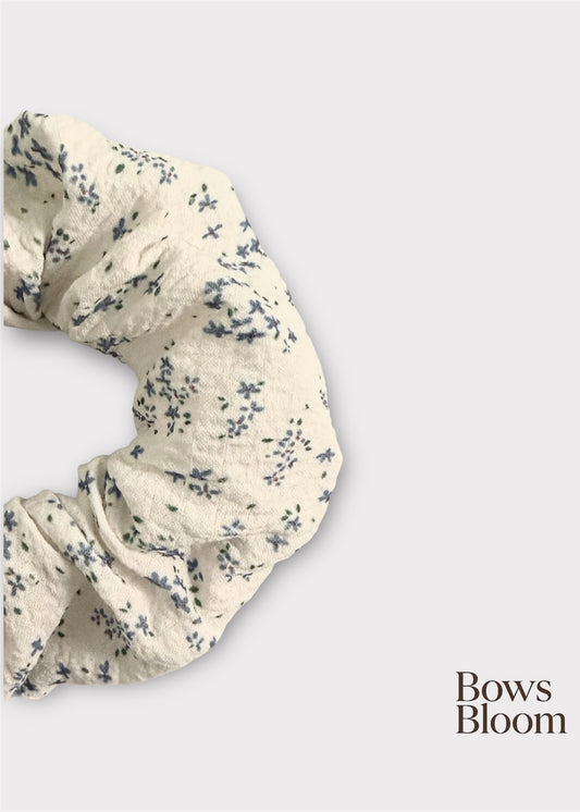 Close-up of white textured scrunchie with blue ditsy flowers showing crinkled fabric