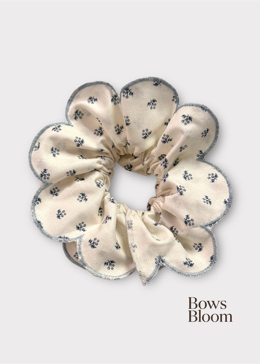 Cream floral scrunchie with scalloped blue edge, full product on light background.